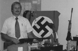 ATF agent John Osburg with weapons and flag seized in 1981 from Canadian and U.S. racists planning Operation Red Dog, a coup on the island of Dominica.